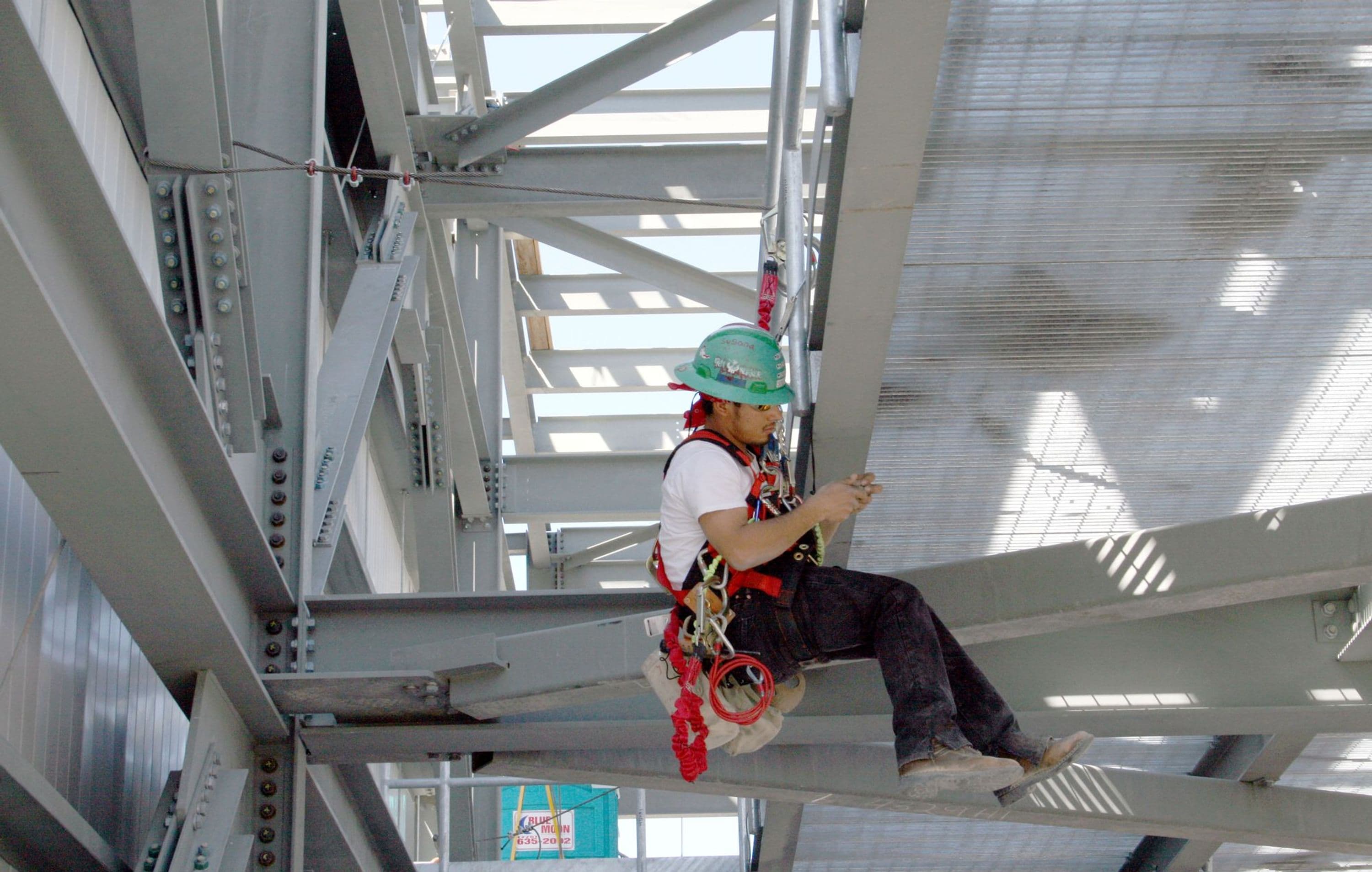 Craft steel worker suspended from safety harness