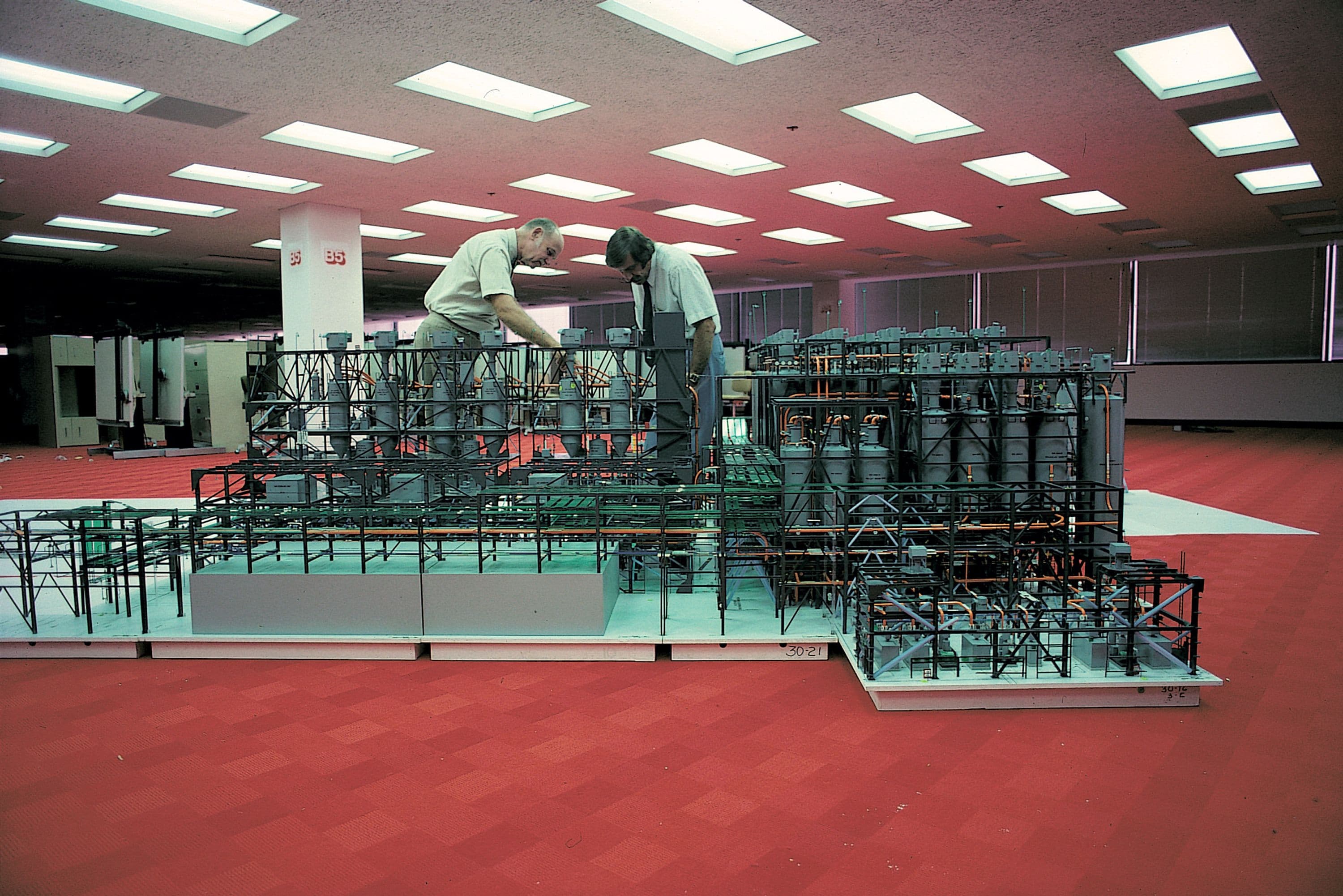 Two Fluor employees working on model of petrochemical complex